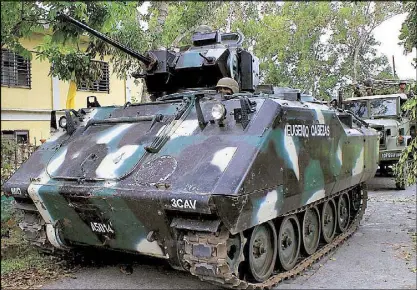  ??  ?? An armored vehicle waits near the town hall in Butig, Lanao del Sur after a military operation in the area. Three soldiers and 42 militants have been killed and more than 20,000 displaced during a week of fighting.
AFP