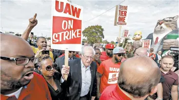  ?? BILL PUGLIANO/TNS ?? Presidenti­al hopeful Sen. Bernie Sanders walks the picket line with striking UAW members as they picket GM in in Detroit.