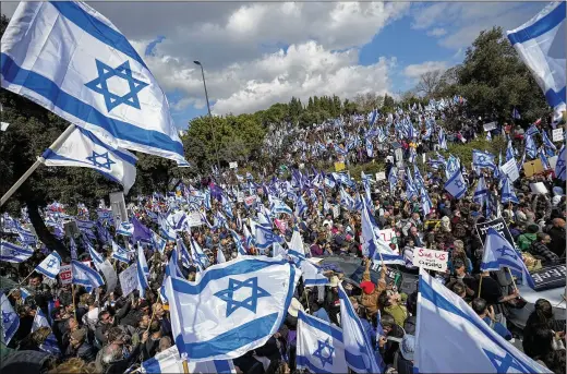  ?? OHAD ZWIGENBERG/ASSOCIATED PRESS ?? Israelis wave national flags Feb. 13 outside the Knesset, Israel’s parliament, during a protest in Jerusalem against plans by Prime Minister Benjamin Netanyahu’s new government to overhaul the judicial system, which it claims will bring an unelected judiciary under control.