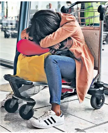  ??  ?? A passenger sleeps on a luggage trolley at Heathrow airport, which saw mass cancellati­ons of short-haul flights continue yesterday