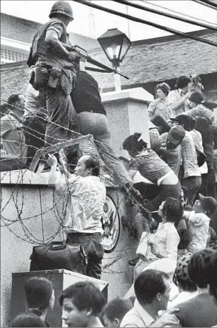  ?? Neal Ulevich
Associated Press ?? IN APRIL 1975,
South Vietnamese tried to scale the wall at the U.S. embassy in Saigon.