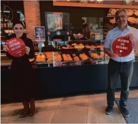  ??  ?? Nigina Ihle und Jürgen Schweier mit den neuen Bodenaufkl­ebern, die an den richtigen Abstand erinnern.