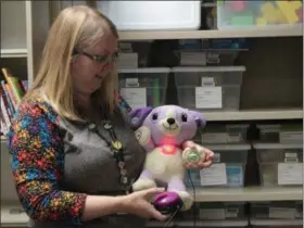  ?? KRISTI GARABRANDT — THE NEWS-HERALD ?? Children’s librarian Sarah Vargo shows off some of the adaptive toys for children with special needs available for check-out at the Willoughby Public Library. The animated stuffed animal activated by squeezing a paw is fitted with a large button for those who have difficulty with fine motor skills.