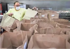  ?? JOE RONDONE/THE COMMERCIAL APPEAL ?? David Fleischhac­ker, executive director of the Baron Hirsch Congregati­on, helps to organize 70 Passover meals prepared by Zayde's NYC Deli at the Synagogue Thursday planned to be delivered to seniors and those in need on the holiday.