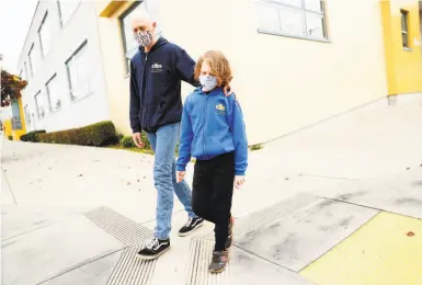  ?? Photos by Scott Strazzante / The Chronicle ?? Bryan McDonald and his secondgrad­e son, Travis, walk outside Dianne Feinstein Elementary School.