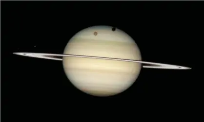  ??  ?? Titan casts a large shadow on to Saturn’s north polar hood in this image taken by Hubble in 2009. Photograph: Nasa/Rex Shuttersto­ck