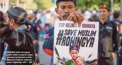  ??  ?? SEORANG lelaki memegang poster ketika menyertai tunjuk perasaan membantah tentera Myanmar di Jakarta, Indonesia pada 8 September 2017. - AFP