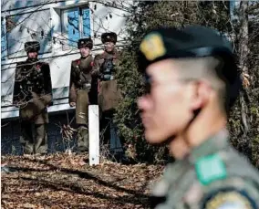  ?? LEE JIN-MAN/AP ?? North Korean soldiers look at the South side as a South Korean stands guard near the border between the two.