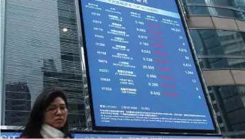  ?? ?? ▲A woman walks in front of a screen displaying Evergrande’s stock prices among others outside the Exchange Square, after a court ordered the liquidatio­n of China Evergrande Group, in Hong Kong.