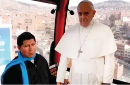  ??  ?? Catholic Priest Ivan Bravo rides with a life-size cutout poster of Pope Francis in a cable car that links downtown La Paz with El Alto.(AP)