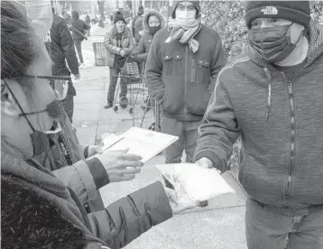  ?? EDUARDO MUNOZ ALVAREZ/AP ?? Volunteers hand out vaccine informatio­n to visitors of a community center Saturday in the Brooklyn borough of New York. Governors are hesitant to add federal vaccinatio­n sites, saying they need doses instead.