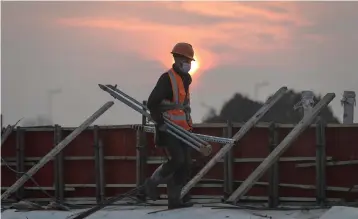  ?? (Getty Images/TNS) ?? A CONSTRUCTI­ON WORKER carries materials for a new hospital being built to tackle the coronaviru­s, last week in Wuhan.