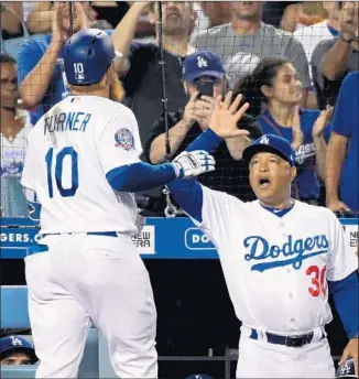  ?? Harry How Getty Images ?? JUSTIN TURNER is greeted by manager Dave Roberts after hitting a solo home run in the fifth inning against San Francisco’s Madison Bumgarner to put the Dodgers ahead 2-0.