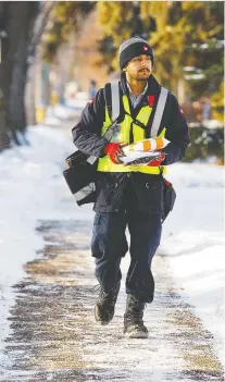  ?? DAVID BLOOM ?? Canada Post workers are dealing with heavy package volumes as they work under strict protocols due to the pandemic. Above, an employee delivers mail in the Garneau neighbourh­ood Wednesday.