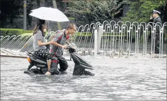  ?? PHOTO: CHINA DAILY/REUTERS ?? People attempt to ride along a flooded street during heavy rainfall in Beijing, China, this week
