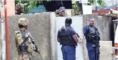  ?? FILE ?? Police assigned to the zone of special operations check identifica­tion documents at a checkpoint in the west Kingston garrison of Denham Town.