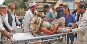  ?? AP PHOTO/WALI SABAWOON ?? A wounded man is brought by stretcher into a hospital after a mortar was fired by insurgents in the Haskamena district of Jalalabad east of Kabul, Afghanista­n, on Friday.