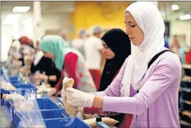 ??  ?? Experts say those who help others were most likely to thrive. Jackie Mahjoub is seen in 2013 packages rice while volunteeri­ng during the fasting hours of Ramadan at the Regional Food Bank of Oklahom in Oklahoma City. [SARAH PHIPPS/THE OKLAHOMAN ARCHIVES]