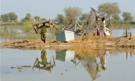  ?? FAREED KHAN/AP ?? Villagers retrieve belongings Oct. 25 amid floodwater­s lingering from the summer in the Sohbat Pur district of Pakistan’s Baluchista­n province.