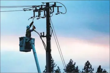  ?? Rich Pedroncell­i Associated Press ?? A WORKER for Pacific Gas and Electric repairs a power line in f ire- ravaged Paradise, Calif. The utility shuts off power out of concern that wind could damage equipment, creating a spark that could spread into a wildfire.
