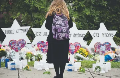  ?? Brendan Smialowski, Getty Images ?? A woman stands at a memorial outside the Tree of Life synagogue after a shooting there left 11 people dead in Pittsburgh on Oct. 27. The number of anti-Semitic crimes reported nationally rose about 37 percent last year.