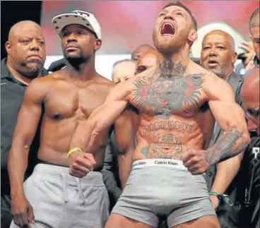  ?? AFP ?? UFC lightweigh­t champ Conor McGregor (right) screams after the weighin as Floyd Mayweather Jr looks on in Las Vegas on Saturday.