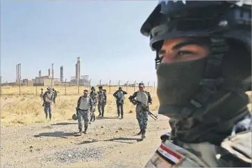  ?? Ahmad al-Rubaye AFP/Getty Images ?? AN OIL PRODUCTION plant provides a backdrop for Iraqi forces heading toward the city of Kirkuk.