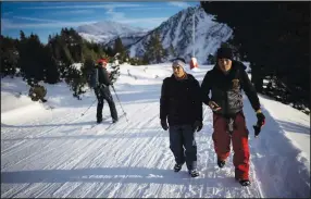  ?? ?? A skier passes by Hamza (left) and Rezaie on Dec. 12 as they trek through the French-Italian Alps.