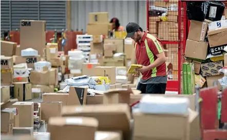  ??  ?? Ryan Walmsley sorts packages ready for delivery at the NZ Post parcel depot on Smart Rd in New Plymouth.