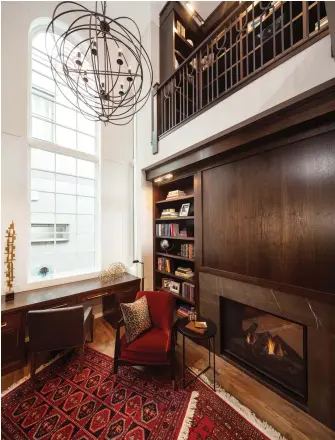  ??  ?? Walnut millwork offers a warm display of shelving, cabinets, and a custom desk, revealing a rich and traditiona­l setting that rises to the twenty-foot ceiling. A Palladian-style window with corner side lite features provides soaring natural light.