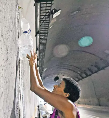  ??  ?? A woman collects water from a spout in a highway tunnel in Caracas. Venezuela has experience­d near-daily blackouts since March 7.
‘We have options, and it would be a mistake for the Russians to think they have a free hand’
