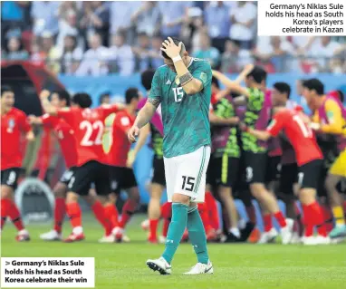  ??  ?? > Germany’s Niklas Sule holds his head as South Korea celebrate their win Germany’s Niklas Sule holds his head as South Korea’s players celebrate in Kazan