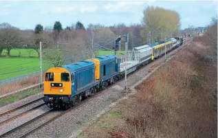  ?? DOUG BIRMINGHAM ?? Type 1s Nos. No 20205+20189, top-and-tailed with Nos. 20142+20007 plus barrier wagons, are captured at Moore (Cheshire) on March 17 hauling new Merseyrail EMU No. 777049 as the 6X28/10.49hrs Warrington Arpley Sidings to Crewe. The EMU had arrived at Arpley on March 16, with classmates Nos. 777013 and 777015, the ‘20s’ taking these two forward to Kirkdale depot before returning to take No. 777049 to Crewe for storage. In the background is Acton Grange Junction and the bridges over the Manchester Ship Canal and River Mersey.