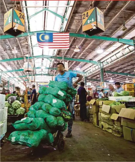  ?? FILE PIC ?? A foreign worker at the bustling Selayang wholesale market in Kuala Lumpur in January. More locals are now willing to take up whatever skilled or unskilled jobs they can find.