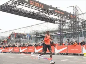  ?? Luca Bruno / Associated Press ?? Olympic marathon champion Eliud Kipchoge crosses the finish line of a marathon race at the Monza Formula One racetrack in Italy. No human has ever run 26.2 miles faster than Kipchoge’s 2 hours, 25 seconds.