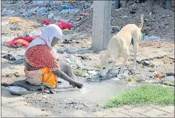  ?? HIMANSHU VYAS/HT PHOTO ?? A homeless woman washes her feet in a ditch, near SMS Medical college on JLN Road in Jaipur.