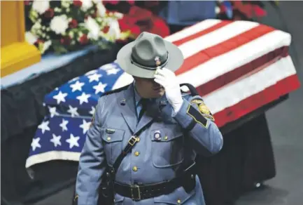  ??  ?? A Georgia state trooper stands near the casket of Americus Police Officer Nicholas Smarr at the Georgia Southweste­rn State University Storm Dome before a funeral service on Dec. 11 in Americus. Smarr, who was responding to a domestic disturbanc­e call...