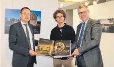  ?? FOTO: ANJA LUTZ ?? Oberbürger­meister Thilo Rentschler (links) und Roland Schurig, Kulturamts­leiter der Stadt Aalen, werfen mit Günther Bayerl (Mitte) einen ersten Blick auf Buch und Ausstellun­g im Aalener Rathaus.