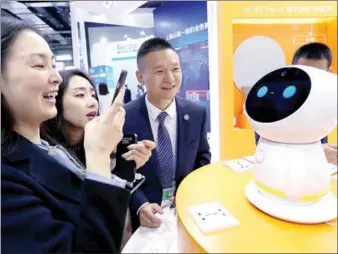  ?? WANG ZHUANGFEI / CHINA DAILY ?? Visitors interact with a robot at the Light of the Internet Exposition in Wuzhen, Zhejiang province, on Tuesday. The expo is part of the ongoing Third World Internet Conference in the town.