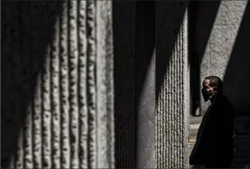  ?? Steph Chambers/Post-Gazette ?? A masked pedestrian makes his way through a shaft of light on Wednesday along Federal Street on the North Shore.