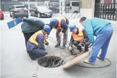  ??  ?? Workers pull cables out of a gutter on a street in Beijing on March 23. China urged the United States on Friday to “pull back from the brink” as President Donald Trump’s plans for tariffs on up to US$60 billion in Chinese goods brought the world’s two largest economies closer to a trade war. — AFP photo