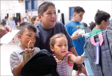  ?? RECORDER PHOTO BY CHIEKO HARA ?? Incoming first grader Elianna Deleon, 5, gets her backpack after her cousin Francisco Mendez, 5, left, received his Friday, July 20 at the third annual Grandparen­ts Raising Grandchild­ren’s backpack giveaway at Jim Maples Academy in Portervill­e.