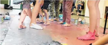  ??  ?? A collective of young artists showed flair by taking off their shoes and painting the background to the mural with their feet.