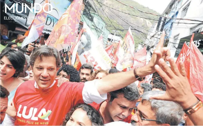  ??  ?? ► Fernando Haddad, acompañado de su candidata a la vicepresid­encia, Manuela D’Ávila (a la izquierda) en un mitin en la favela Rocinha, en Río de Janeiro.