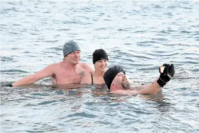  ?? CATHIE COWARD THE HAMILTON SPECTATOR ?? Soren and Leigh Michelsen and Charles Steinhoff all enjoy a swim in the freezing water of Lake Ontario Sunday morning. “Your whole body feels like it’s on fire,” says Steinhoff, happily.