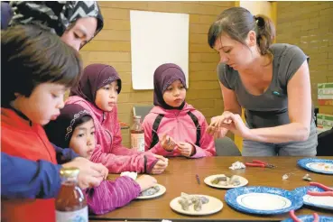  ?? RAY CHAVEZ/STAFF ?? Kristi Holohan, right, community director of the Rock, Paper, Scissors art collective, shows kids how to make jewelry during a jewelry-making class at the Oakland Public Library’s West Oakland branch.