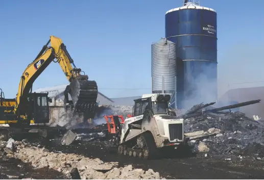  ??  ?? Workers were busy Tuesday morning clearing the scene of a fire the previous evening that destroyed a barn at a farm on Lobsinger Line west of St. Clements.