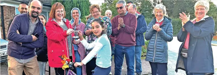  ?? ?? Photo shows Zeynep receiving her trophy from Chris Bantock and congratula­tions from fellow neighbours.