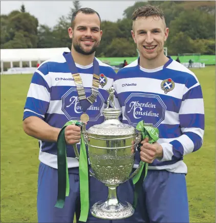  ?? Photo: Kevin McGlynn ?? Two-goal hero Evan Menzies, left, was voted man of the match and received the Albert Smith Memorial Medal holds the Camanachd Cup with Andy MacKintosh, Newtonmore club captain.