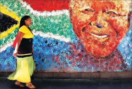  ?? Picture:REUTERS ?? IN HIS HANDS: A pedestrian passes a handprint mural of Nelson Mandela in Cape Town.